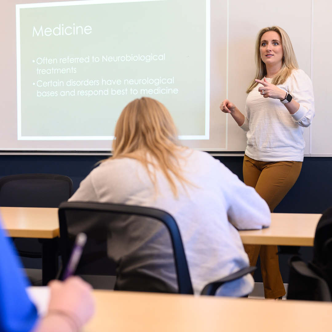 Professor at a white board in front of a class of students