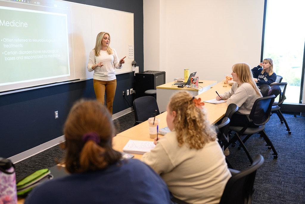 Instructor in the front of class presenting on a whiteboard
