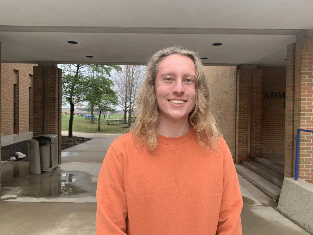 man in orange shirt smiling in front of tunnel