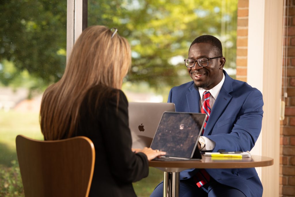 man and woman sitting at a table working on laptops