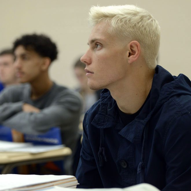 Student in classroom setting paying close attention to instructor's lesson