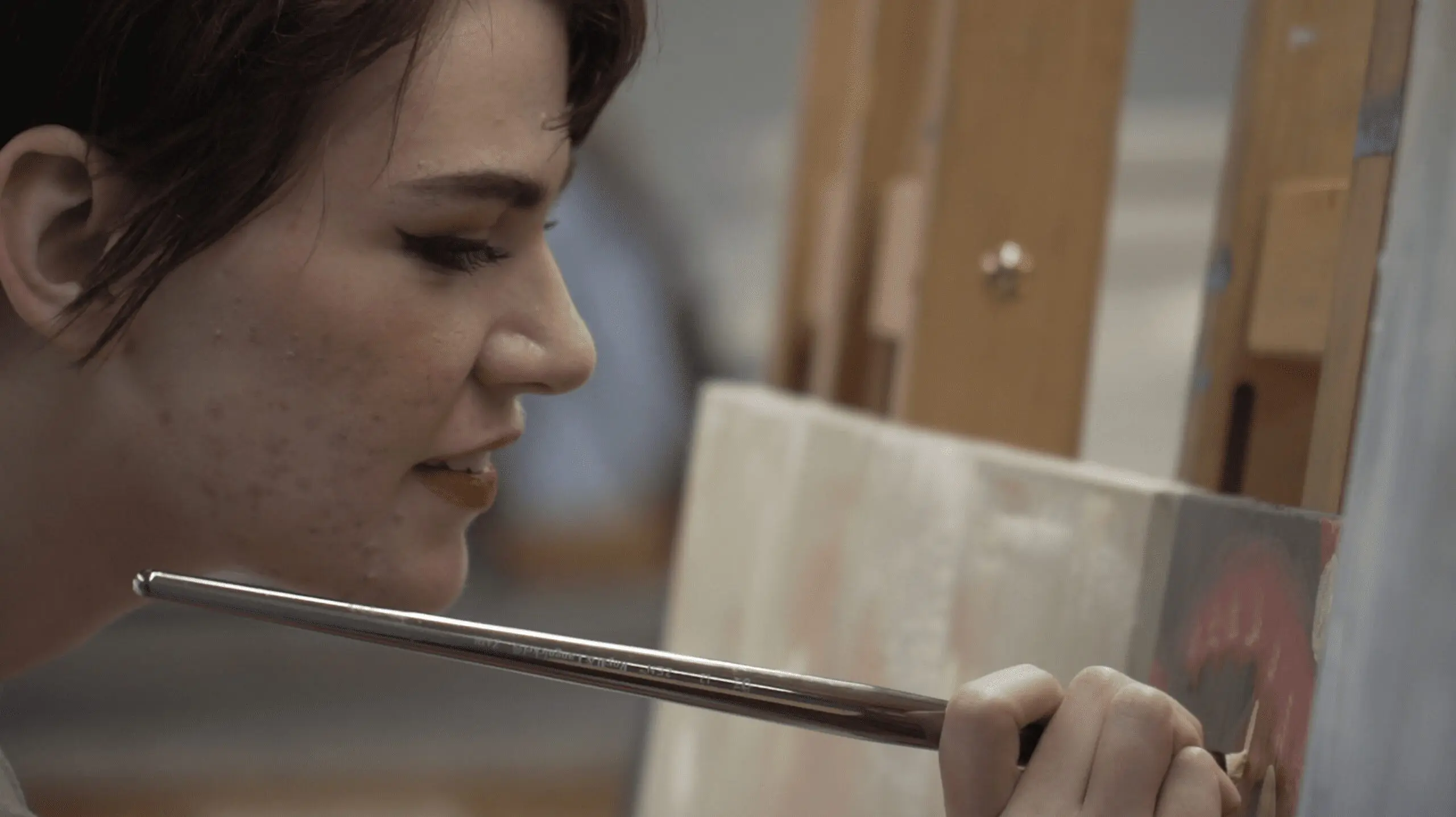 Student artist painting on canvas during class.
