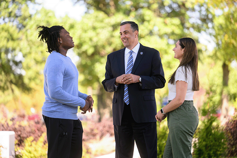 President Chillo and students talking while enjoying a sunny day on campus